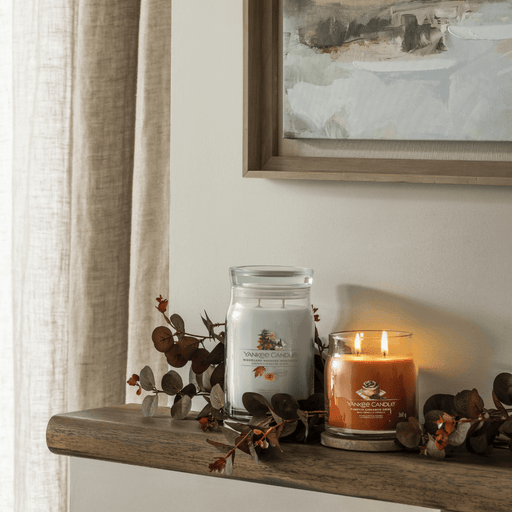 Yankee Candle Pumpkin Cinnamon Swirl medium Signature jar scented candle lit on a mantel with autumn decor