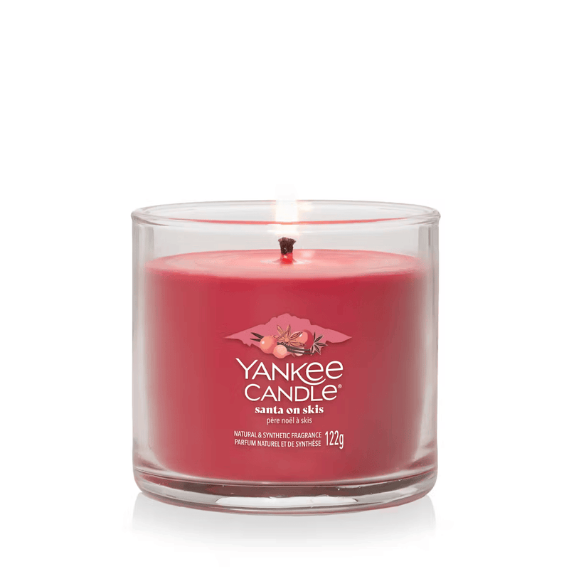 Santa on Skis small tumbler candle lit with deep red wax in clear glass