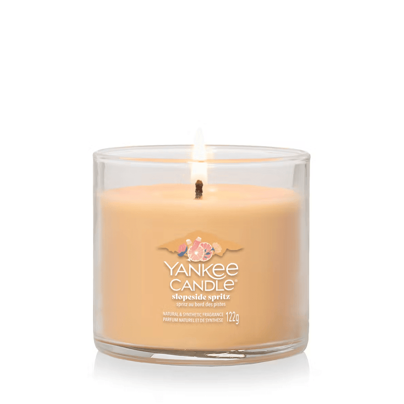 Yankee Candle Slopeside Spritz small tumbler lit, peach-orange wax in clear glass