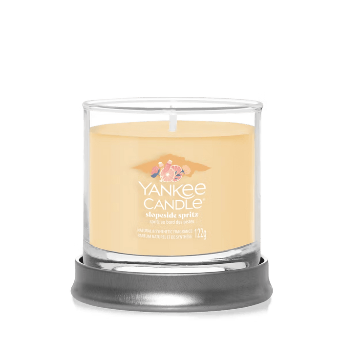 Slopeside Spritz small tumbler candle on round metal stand with soft orange wax